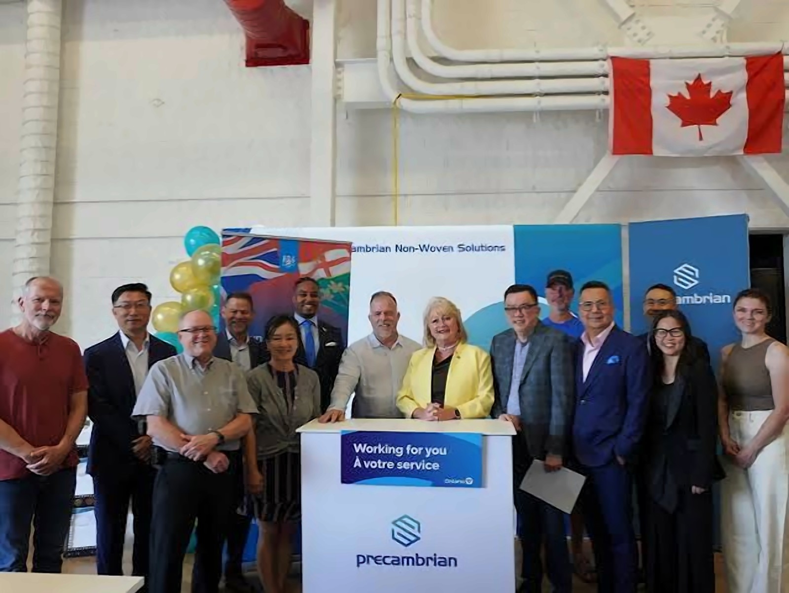 Precambrian team and provincial guests at the Newmarket plant, gathered around a Precambrian Non-Woven Solutions podium