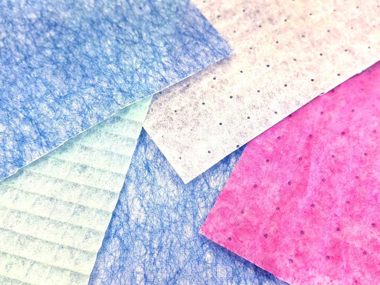 Coloured nonwoven HVAC media sheets fanned out, fibre structure visible