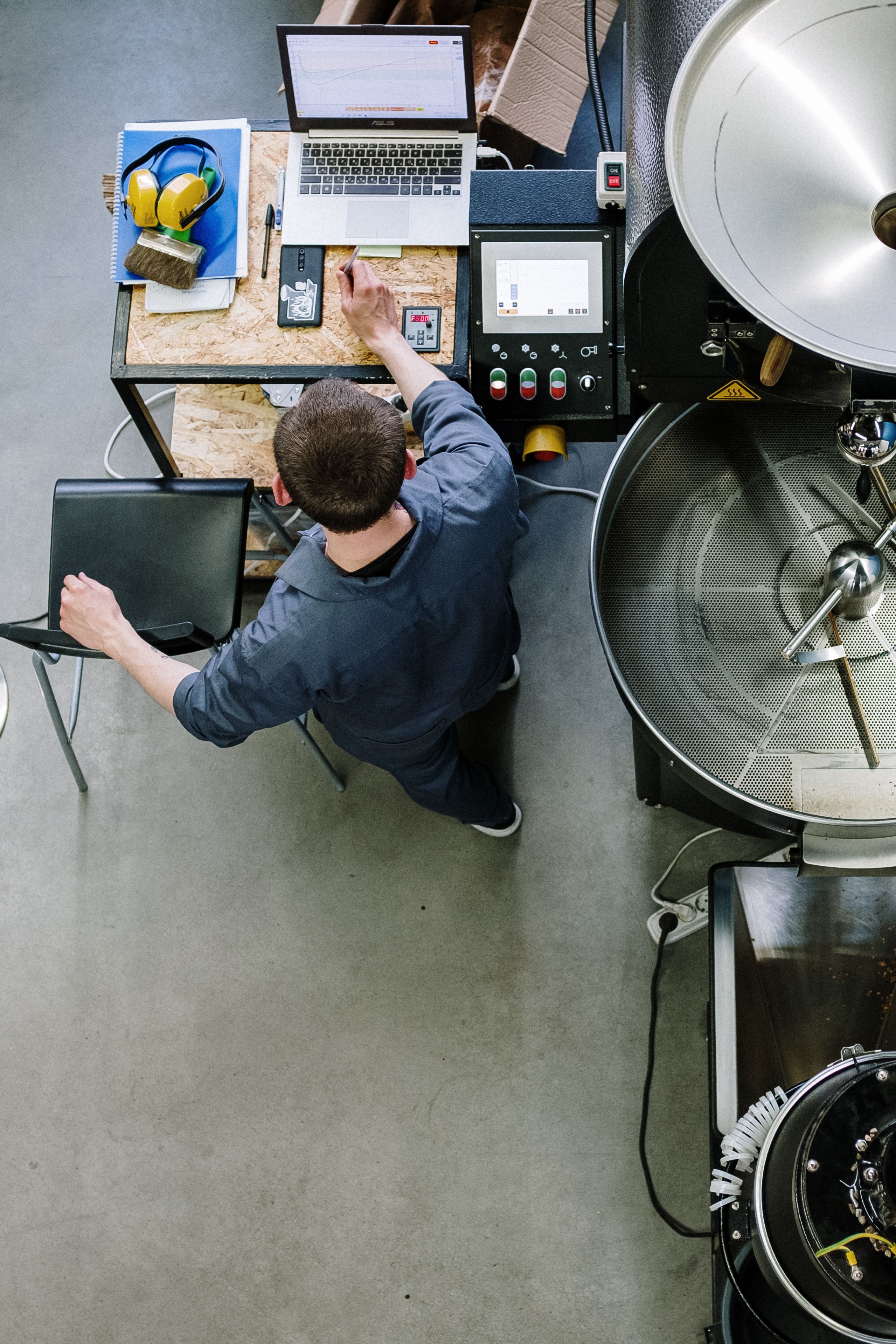 Technician checking process data on a laptop beside a production machine